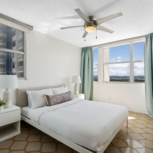 Drift off to sleep in comfort! This serene bedroom features a plush queen-sized bed and expansive windows offering captivating views of the distant mountains and cityscapes.