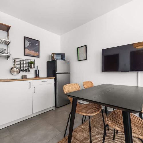 Prepare meals, enjoy your meals, and unwind in this well-equipped kitchen area, complete with modern appliances, a dining table, and a TV.