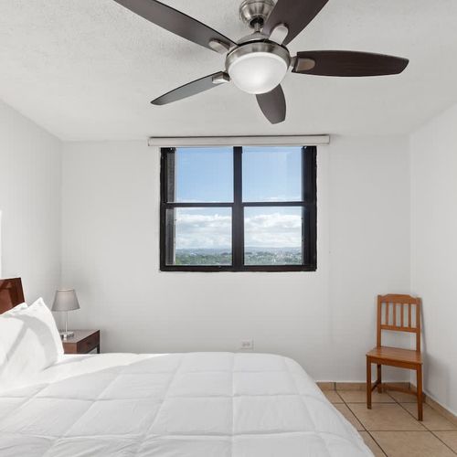 Peaceful bedroom with natural light and a calming fan.