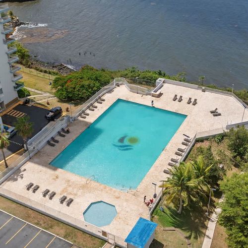 Experience the ultimate resort lifestyle! This incredible aerial view showcases our inviting pool, perfectly situated with the stunning backdrop of the tranquil bay and lush surroundings – your personal slice of paradise.