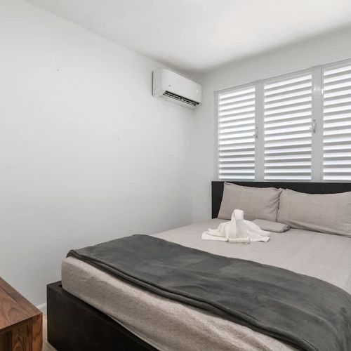 A bright and airy room with white linens and a cozy throw blanket.