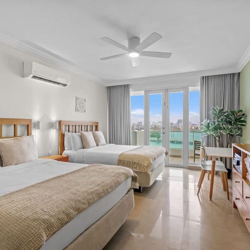 Spacious and inviting bedroom with direct access to a private balcony, offering panoramic water and city vistas.