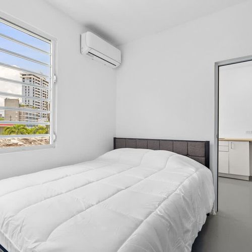 Wake up refreshed in this bright and airy bedroom, featuring a comfortable queen-sized bed adorned with crisp, white linens, ensuring a peaceful night’s sleep.