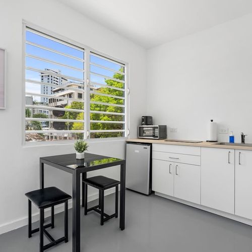 A sleek, white kitchenette complements the minimalist design, offering guests both style and functionality during their stay.
