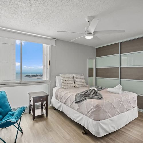 Sleep in comfort with a view! This serene primary bedroom offers a plush queen-sized bed and stunning glimpses of the ocean, ensuring a peaceful and rejuvenating night's sleep.