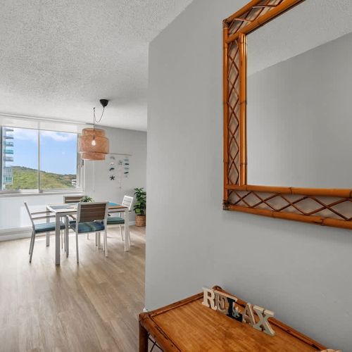 "Panoramic living experience! This inviting perspective captures the expansive living and dining areas, seamlessly leading your eye towards the bright balcony and the beautiful outdoor views beyond