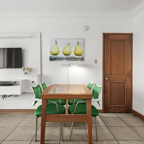 Gather around this stylish dining table, perfectly sized for intimate meals or lively conversations. The contemporary design, vibrant green chairs, and unique artwork create a welcoming atmosphere for your culinary delights.