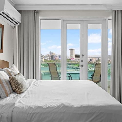 Relax and unwind in this serene bedroom, offering direct balcony access and an incredible panorama of the lagoon and cityscape. Enjoy the natural light and the gentle breeze, creating a peaceful sanctuary for your escape.