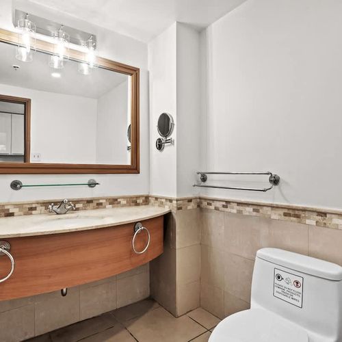 Step into our thoughtfully designed bathroom, featuring a stylish vanity with ample counter space and a large mirror. Every detail is considered for your comfort and convenience, with an accessible layout