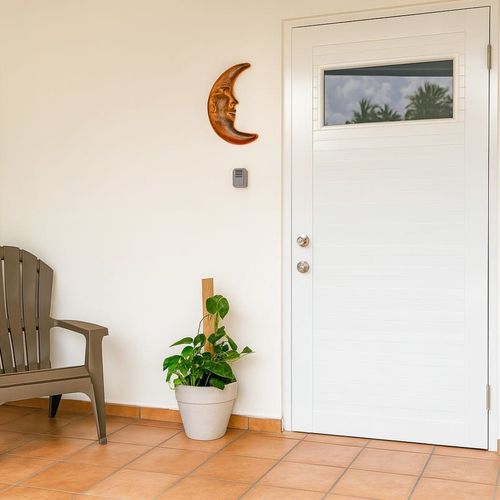 Welcoming front entrance to Luna Suite with a cozy chair, potted plant, and moon wall decor. Enjoy a peaceful stay with warm tile floors and a private, serene vibe at Casa Natura.