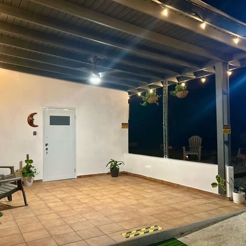 Spacious and peaceful front terrace with hanging plants and string lights—ideal for relaxing evenings. A welcoming entrance to Luna Suite at Casa Natura, blending comfort and nature effortlessly.