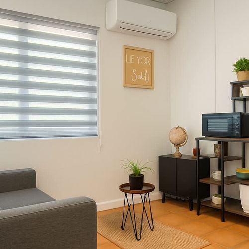 Cozy corner with natural light, coffee station, microwave, and modern decor. Features a comfy armchair, indoor plants, and warm tile floors—perfect for relaxing mornings at Luna Suite, Casa Natura.