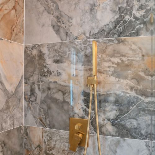 The recently upgraded bathroom is well-lit, thoughtfully stocck with the essential amenities, and adorned with beautiful marble tiles and a delightful rain shower.