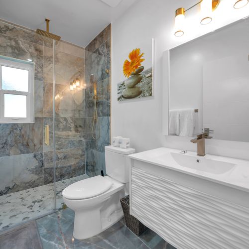 The recently upgraded bathroom is well-lit, thoughtfully stocck with the essential amenities, and adorned with beautiful marble tiles and a delightful rain shower.