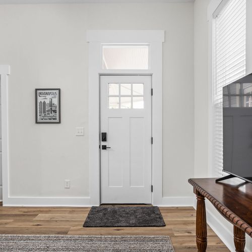 Step inside to a bright, inviting entryway with a modern door, cozy rug, and local Indianapolis art—a warm welcome awaits!