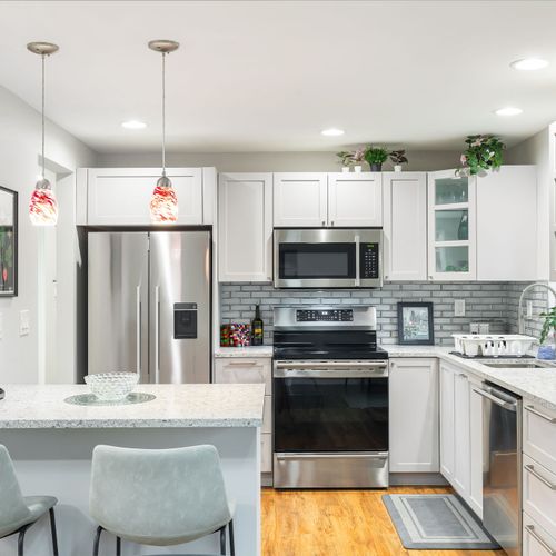 A clean, modern kitchen with a counter and stools, perfect for casual gatherings or quick meals.