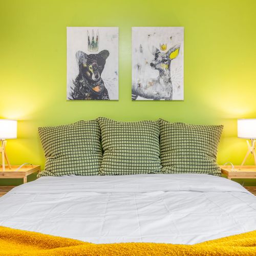 This cozy bedroom boasts lush green walls and a stunning lampshade, creating a peaceful and stylish space.