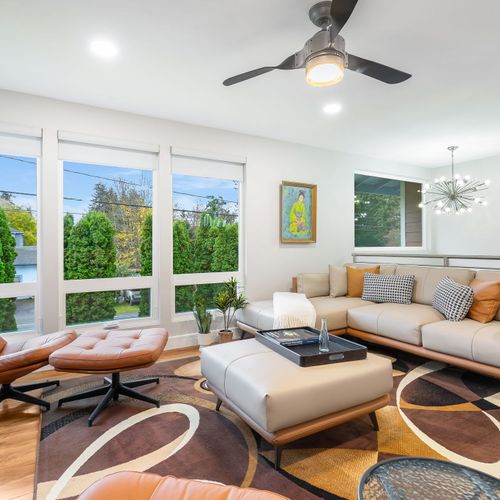 Spacious living room flooded with natural light and framed by picturesque tree views.