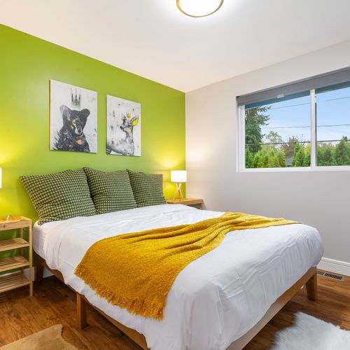 This cozy bedroom boasts lush green walls and a stunning lampshade, creating a peaceful and stylish space.