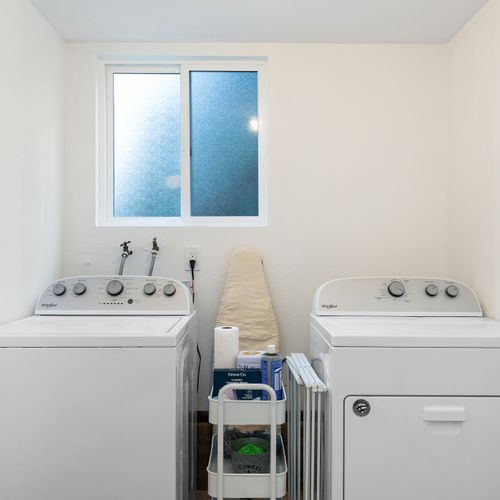 The laundry area is equipped with a modern washing machine and a selection of detergents for your convenience.