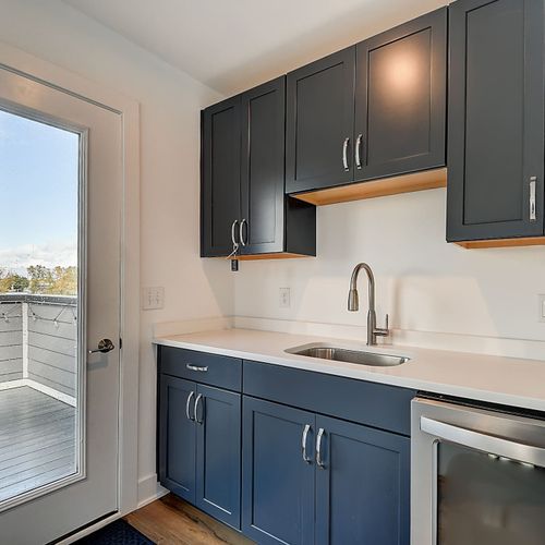 A convenient wet bar at the entrance of the rooftop deck, complete with a mini fridge, sink, and cabinets.