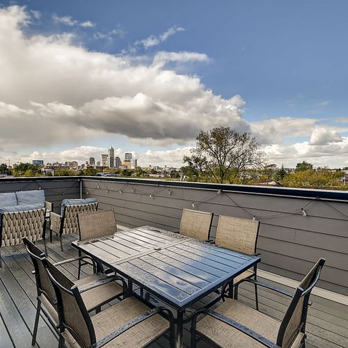 The rooftop deck offers comfortable furniture, a dining table for six, and stunning city skyline views—perfect for relaxing or enjoying a meal with a view.