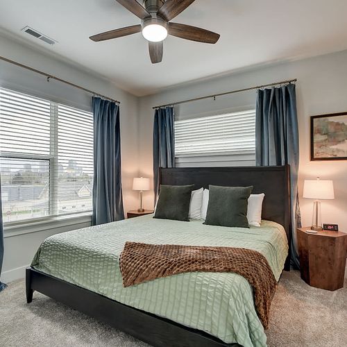 Skyline view bedroom with King bed featuring matching bedside tables, soft lighting, and natural light through large windows.