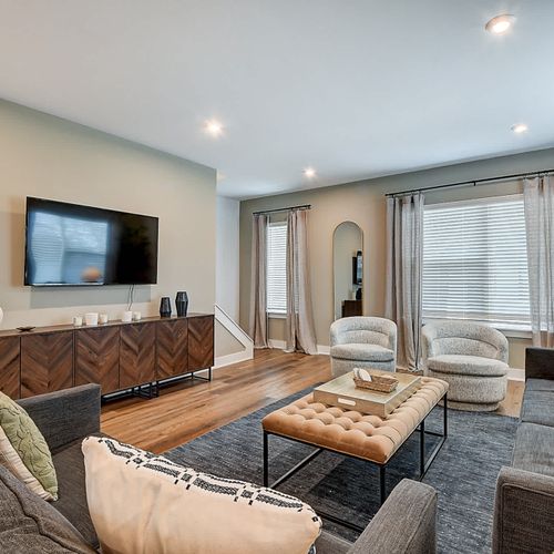 Step into your modern space, featuring a large couch, comfy chairs, and loveseat, TV, and warm decor.