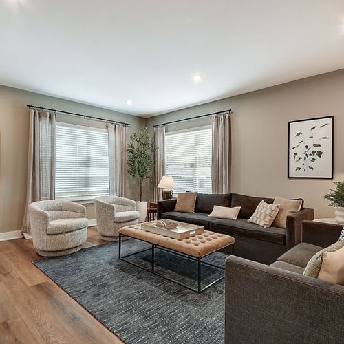 Step into your modern space, featuring a large couch, comfy chairs, and loveseat, TV, and warm decor.