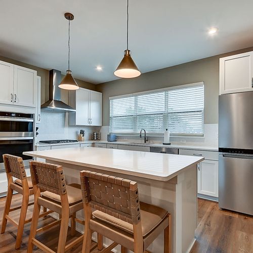 This modern kitchen boasts stainless steel appliances, elegant pendant lighting, and bar seating, offering both style and comfort for a luxurious stay!