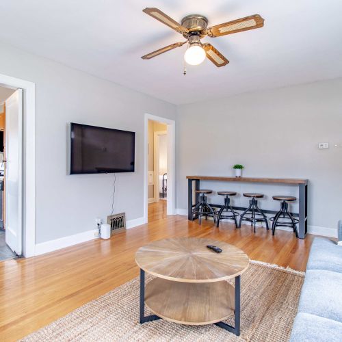 A cozy living room featuring a plush couch with soft throw pillows, two stylish accent chairs arranged for conversation, a sleek coffee table at the center, accompanied with a bar table and bar stools.