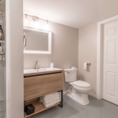 A bright and clean full bathroom featuring a modern sink, a sleek toilet, and a shower perfect for relaxing soaks or refreshing showers. Stocked with fresh towels, toiletries, and all the essentials for a comfortable stay.