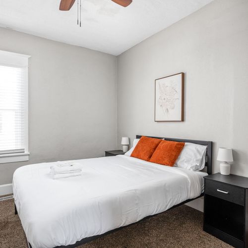 The second bedroom off of the living room with thoughtful cozy decor, a queen bed, nightstands and lamps.