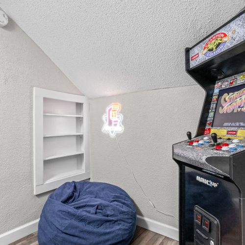 Fun-filled nook featuring a classic arcade machine, vibrant arcade sign, and a comfy bean bag chair—the perfect spot for some downtime!