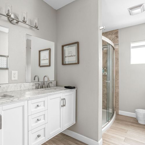 This upstairs bathroom features a modern double floating vanity, cozy decor, and a standing full shower.