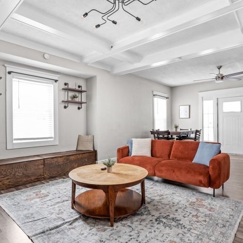 Step into our modern living room with industrial shelving and lighting. Featuring a comfy couch, thoughtful decor, and a smart TV for your convenience.