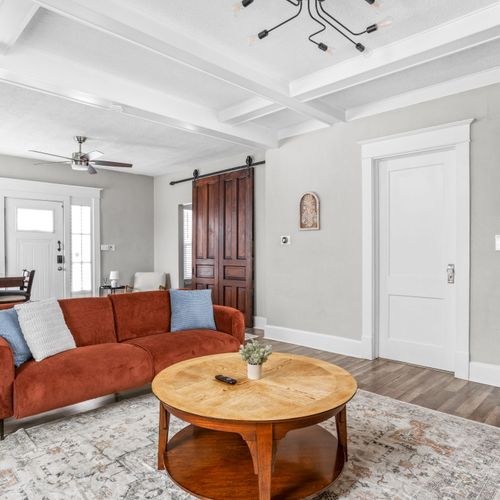 Step into our modern living room with industrial shelving and lighting. Featuring a comfy couch, thoughtful decor, and a smart TV for your convenience.