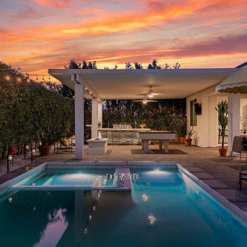 Patio with pool and hot tub at sunset