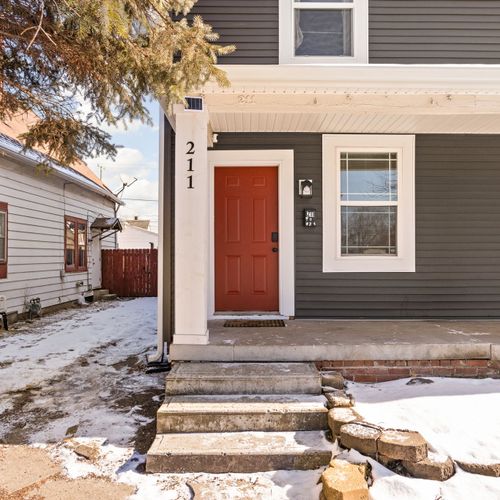 Welcome to your stay! A bold red door, a porch, and an inviting walkway set the tone for your perfect getaway.