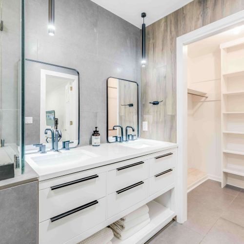 Bathroom 1 features a modern double vanity with ample storage, sleek finishes, and direct access to a spacious walk-in closet.