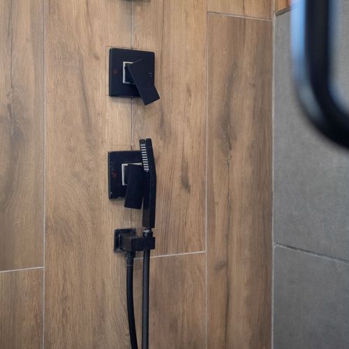 Modern shower with sleek black fixtures and wood-look tiles, offering a luxurious spa-like experience.
