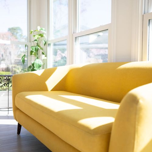Bright and airy living space featuring a vibrant yellow sofa, perfect for relaxing in natural light. ☀️