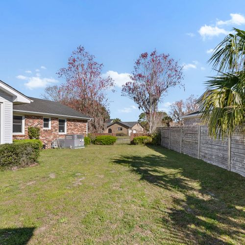 Spacious fenced backyard with lush greenery, perfect for outdoor relaxation and family fun.