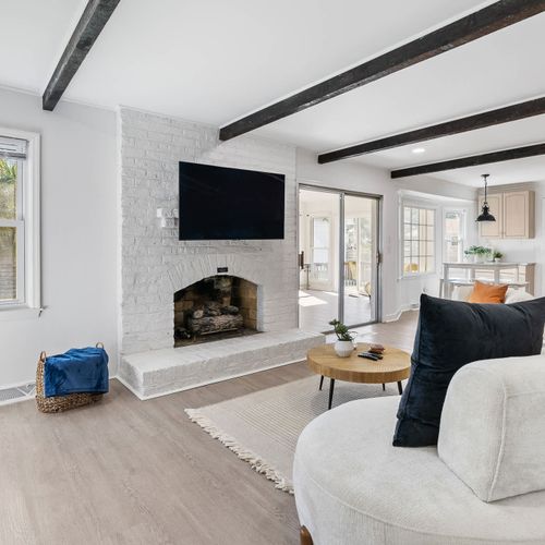 Stylish living room with exposed beams, a cozy fireplace, and modern furnishings — the perfect space to unwind.