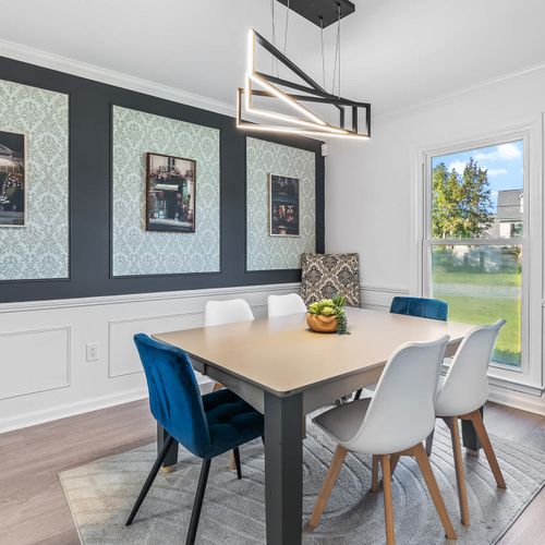 Stylish dining room with modern lighting, chic decor, and a relaxing backyard view.