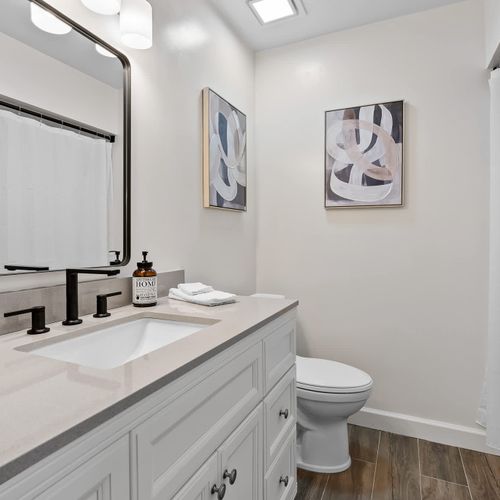 Bright and modern! This elegant bathroom features a sleek vanity with stylish black fixtures, perfect for a refreshing and comfortable stay.