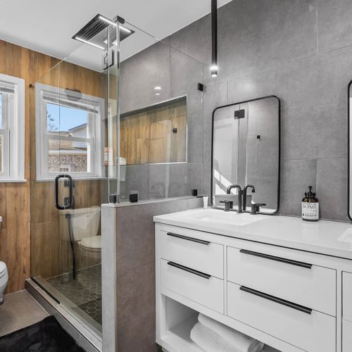Stylish spa-like bathroom with a sleek double vanity, glass shower, and natural light.
