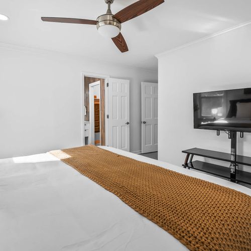 Spacious master suite with a king bed, modern décor, and a cozy entertainment setup.