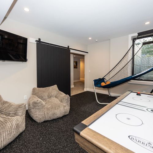 Our basement game room, featuring a smart ROKU TV, basketball game, air hockey table, two comfy chairs, and an arcade machine! We also have a surplus of board games and puzzles ready for your next play!