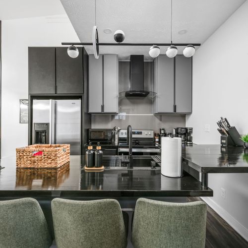Welcome to our modern moody kitchen with 4 bar stools, upgraded appliances, and a stylish, eclectic vibe.